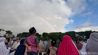 Tampak seorang anak kecil yang memandang langit. Fenomena pelangi itu membuat mereka tertarik. Foto: Eka Rimawati/detikJatim