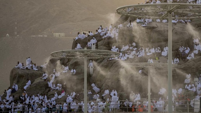 Water mist is sprayed on Muslim pilgrims as they pray on the rocky hill known as the Mountain of Mercy, on the Plain of Arafat, during the annual Hajj pilgrimage, near the holy city of Mecca, Saudi Arabia, Tuesday, June 27, 2023. Around two million pilgrims are converging on Saudi Arabias holy city of Mecca for the largest Hajj since the coronavirus pandemic severely curtailed access to one of Islams five pillars. (AP Photo/Amr Nabil)