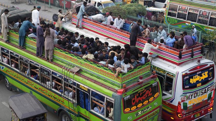 People travel on the rooftop of commuter buses to reach their towns and villagers ahead of Muslim Eid al-Adha, or Feast of Sacrifice holiday, in Lahore, Pakistan, Tuesday, June. 27, 2023. (AP Photo/K.M. Chaudary)