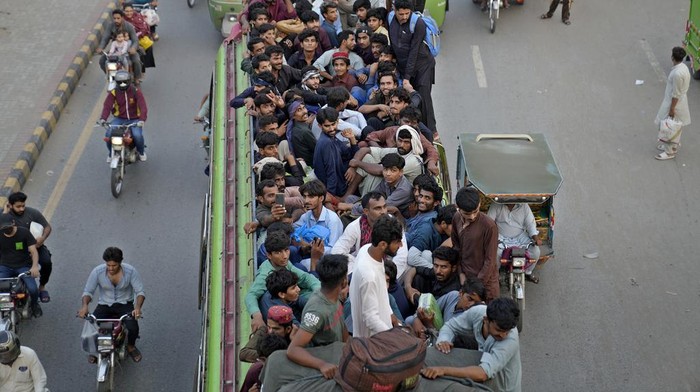 People travel on the rooftop of commuter buses to reach their towns and villagers ahead of Muslim Eid al-Adha, or Feast of Sacrifice holiday, in Lahore, Pakistan, Tuesday, June. 27, 2023. (AP Photo/K.M. Chaudary)
