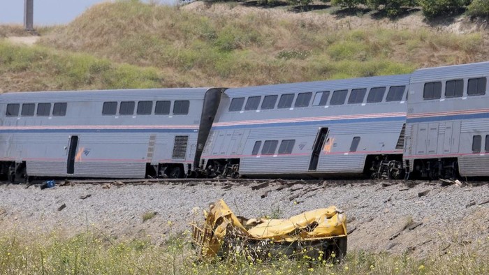 Kereta Amtrak di AS Tergelincir Usai Menabrak Truk A destroyed truck lies next to a derailed Amtrak train in Moorpark, Calif., on Wednesday, June 28, 2023. Authorities say an Amtrak passenger train carrying 190 passengers derailed after striking a vehicle on tracks in Southern California. Only minor injuries were reported. (Dean Musgrove /The Orange County Register via AP)