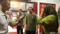 Jokowi berjalan kaki sembari menyapa warganya. Tak hanya itu, ia juga membagikan kaos. 