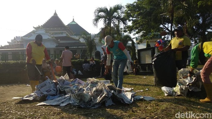 Petugas kebersihan mengumpulkan koran bekas salat Idul Adha.