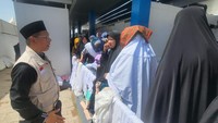 Anggota Timwas Haji DPR, M Husni, berinteraksi dengan jemaah haji perempuan yang sedang mengantre toilet. Foto: Ahmad Toriq/detikcom