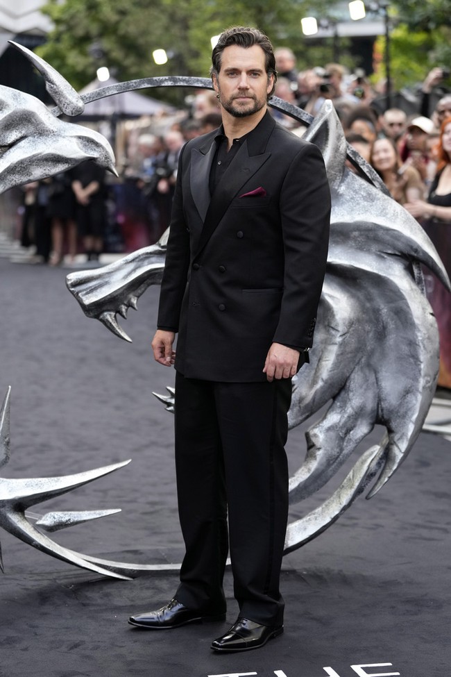 Henry Cavill, yang memerankan karakter Superman selama hampir 10 tahun sejak 2013, tampak gagah dalam balutan setelan serba hitam. Aksen merah hadir lewat sapu tangan yang mengintip dari kantong. (Foto: Scott Garfitt/Invision/AP)
