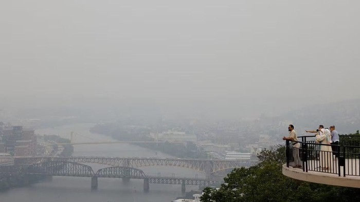 People look on from an observation deck on Pittsburgh’s Mount Washington, as smoke from raging Canadian wildfires hanging over the U.S. Midwest and parts of the East Coast create hazy skies, in Pittsburgh, Pennsylvania, U.S. June 28, 2023. REUTERS/Quinn Glabicki