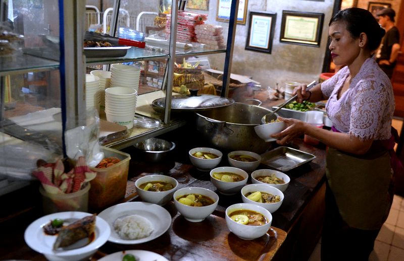 Pramusaji mengantarkan sajian kuliner ikan laut untuk pembeli di Warung Mak Beng, Sanur, Denpasar, Bali, Kamis (29/6/2023). Warung yang telah berdiri sejak tahun 1941 dengan menjual ikan laut goreng, sup kepala ikan laut , dan sup sayur tersebut masuk dalam daftar restoran paling legendaris nomor tiga di dunia versi TasteAtlas. ANTARA FOTO/Fikri Yusuf