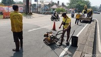 Petugas Bina Marga memperbaiki jalan berlubang di Jalan Raya Kalimalang, Jakarta Timur, Jumat (30/6/2023).