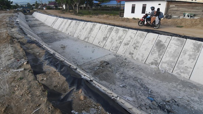 Pengendara sepeda motor melintas di samping proyek rehabilitasi dan rekonstruksi sistem irigasi gumbasa di Kabupaten Sigi, Sulawesi Tengah, Jumat (30/6/2023). Pemerintah melalui Kementerian PUPR berupaya mempercepat penyelesaian jaringan irigasi tersebut untuk dapat difungsikan dan memberdayakan kembali lahan pertanian yang tidak dapat diolah akibat bencana gempa dan likuefaksi pada 2018. ANTARA FOTO/Mohamad Hamzah/rwa.