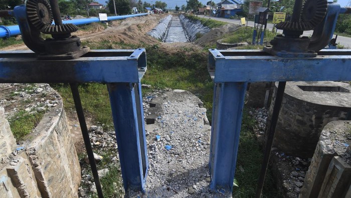 Rehabilisasi dan rekonstruksi sistem irigasi pertanian di Sigi Pengendara sepeda motor melintas di samping proyek rehabilitasi dan rekonstruksi sistem irigasi gumbasa di Kabupaten Sigi, Sulawesi Tengah, Jumat (30/6/2023). Pemerintah melalui Kementerian PUPR berupaya mempercepat penyelesaian jaringan irigasi tersebut untuk dapat difungsikan dan memberdayakan kembali lahan pertanian yang tidak dapat diolah akibat bencana gempa dan likuefaksi pada 2018. ANTARA FOTO/Mohamad Hamzah/rwa.