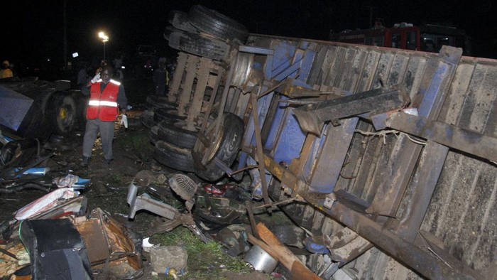 People stand near the wreckage of vehicles after a fatal accident in Londiani, Kenya early Saturday, July 1, 2023, at a location known for crashes about 200 kilometers (125 miles) northwest of the capital, Nairobi. Dozens were killed when a truck rammed into several other vehicles and market traders on Friday evening, police said. (AP Photo)