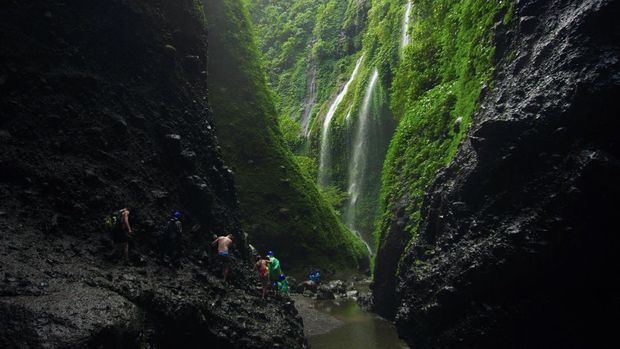Kunjungan wisatawan Air Terjun Madakaripura Wisatawan berjalan di bebatuan saat mengunjungi Air Terjun Madakaripura di Probolinggo, Jawa Timur, Jumat (30/6/2023). Pada libur Idul Adha, kunjungan wisatawan di air terjun tersebut meningkat hingga 100 pengunjung per hari dibanding hari biasa yang hanya mencapai 36 orang per hari. ANTARA FOTO/Irfan Sumanjaya/rwa.