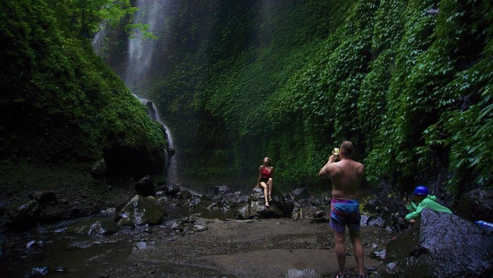 Kunjungan wisatawan Air Terjun Madakaripura Wisatawan berjalan di bebatuan saat mengunjungi Air Terjun Madakaripura di Probolinggo, Jawa Timur, Jumat (30/6/2023). Pada libur Idul Adha, kunjungan wisatawan di air terjun tersebut meningkat hingga 100 pengunjung per hari dibanding hari biasa yang hanya mencapai 36 orang per hari. ANTARA FOTO/Irfan Sumanjaya/rwa.