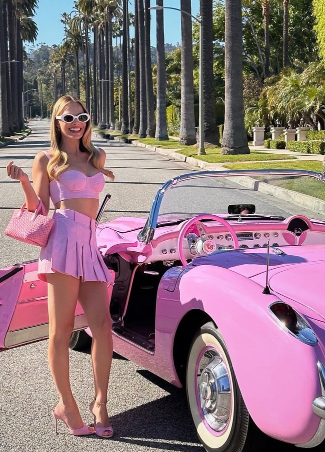Dalam kesempatan lain, Margot Robbie berpose serba pink dengan set crop top, rok mini dan sepatu stiletto Manolo Blahnik. Dia juga menenteng tas Bottega Veneta dan berpose di depan mobil pink. Foto: Instagram/@barbiethemovie @andrewmukamal