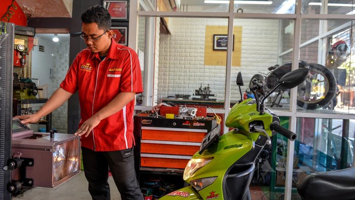 Mekanik melepas baterai motor bbm yang dikonversi ke motor listrik di bengkel Bacip Moto Shop di Bandung, Jawa Barat, Senin (3/7/2023). Bengkel Bacip Moto Shop binaan Bintang Racing Team tersebut merupakan bengkel resmi pemasangan, perawatan, pemeriksaan peralatan instalasi sistem penggerak motor listrik pada kendaraan bermotor dan mendapatkan lisensi Kementerian Perhubungan. Konversi motor tersebut dipatok dengan harga Rp9, 5 juta dengan jarak tempuh rata-rata 40 kilometer. ANTARA FOTO/Raisan Al Farisi/nz
