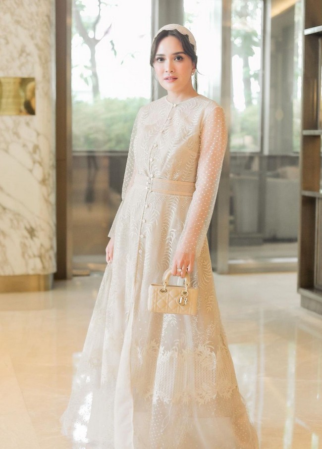 Gaya elegan dan glamor bisa ditonjolkan dengan gaun panjang bernuansa nude untuk acara pesta formal maupun semi-cocktail. Jika enggan memadukan dengan warna cerah, pilih busana yang sarat akan detail dan permainan tekstur, misalnya lace, brokat atau bordiran pada kain. Foto: Instagram/@shandyaulia
