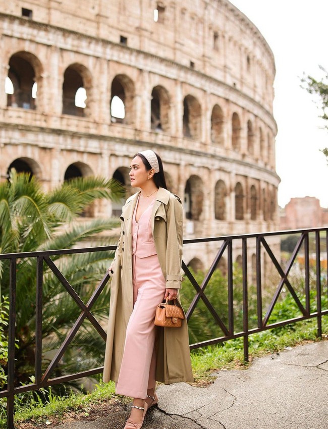Trench coat warna camel bisa membuat penampilan stylish sekaligus elegan. Jadikan trench coat sebagai luaran di atas setelan berwarna pink salem. Padukan dengan flat shoes dan clutch warna senada. Foto: Instagram/@shandyaulia
