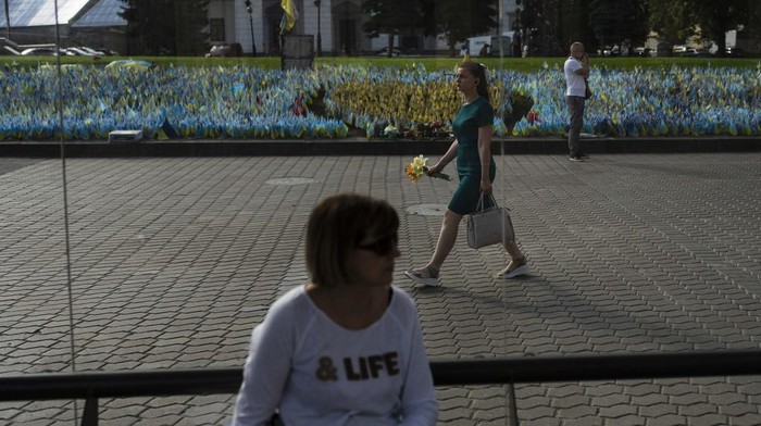 Warga Mengenang Tentara Ukraina yang Tewas dalam Perang A woman with flowers walks past a memorial site honoring people killed in Russian attacks in Kyiv, Ukraine, Monday, July 3, 2023. (AP Photo/Jae C. Hong)