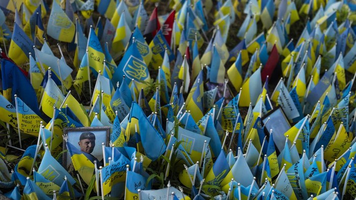 Warga Mengenang Tentara Ukraina yang Tewas dalam Perang A woman with flowers walks past a memorial site honoring people killed in Russian attacks in Kyiv, Ukraine, Monday, July 3, 2023. (AP Photo/Jae C. Hong)