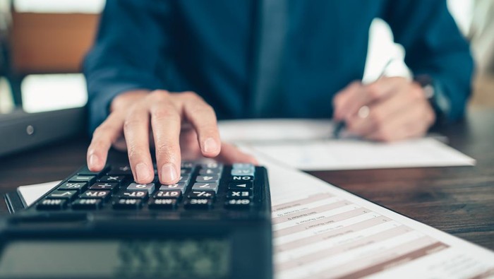 Financial businessman working on desk office using a calculator to calculate calculating corporate income tax data And analyzing charts of financial.  finance and accounting concept.
