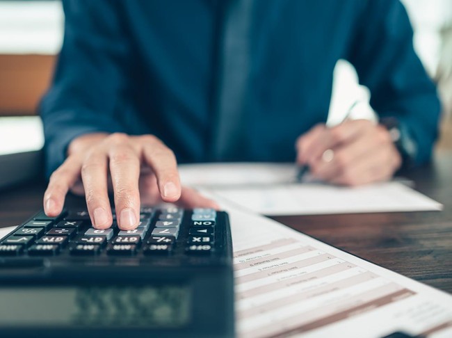 Financial businessman working on desk office using a calculator to calculate calculating corporate income tax data And analyzing charts of financial.  finance and accounting concept.