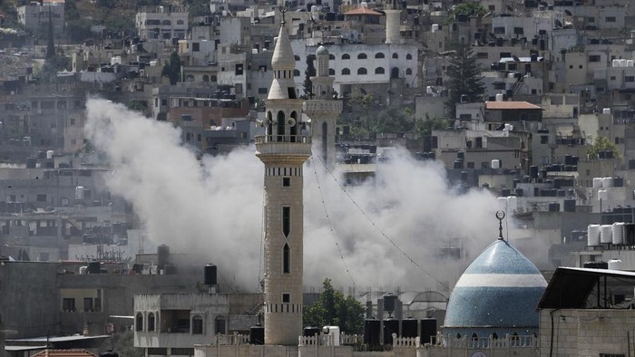 Israel Bombardir Kamp Jenin, 9 Warga Palestina Tewas Smoke rises during an Israeli military raid of the militant stronghold of Jenin in the occupied West Bank, Monday, July 3, 2023. Israeli drones struck targets in a militant stronghold in the occupied West Bank early Monday and hundreds of troops were deployed in the area. Palestinian health officials said at least five Palestinians were killed. (AP Photo/Majdi Mohammed)