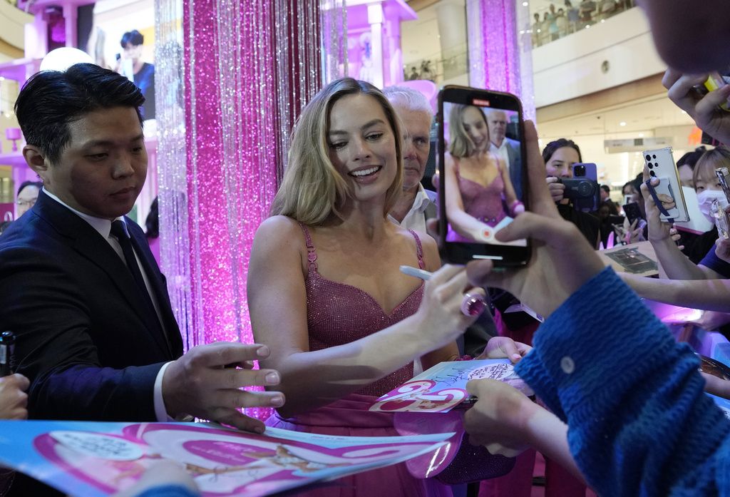Margot Robbie signs autographs for fans during the pink carpet event for the movie 