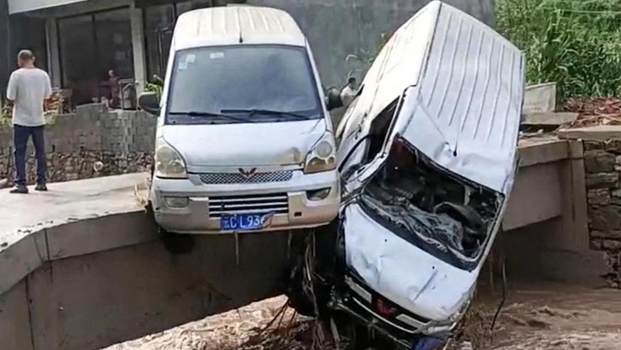 Sejumlah mobil terseret arus banjir di Zhenxiong, Provinsi Yunnan, China, Senin (2/7/2023). Bahkan sebagian mobil nungging karena tersangkut jembatan.