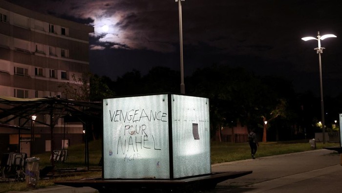 Residents walk past phrases written on walls of buildings at a neighbourhood where Nahel, a 17-year-old teenager, was killed by a French police officer during a traffic stop, in Nanterre, France, July 2, 2023. The phrases written on the walls read 