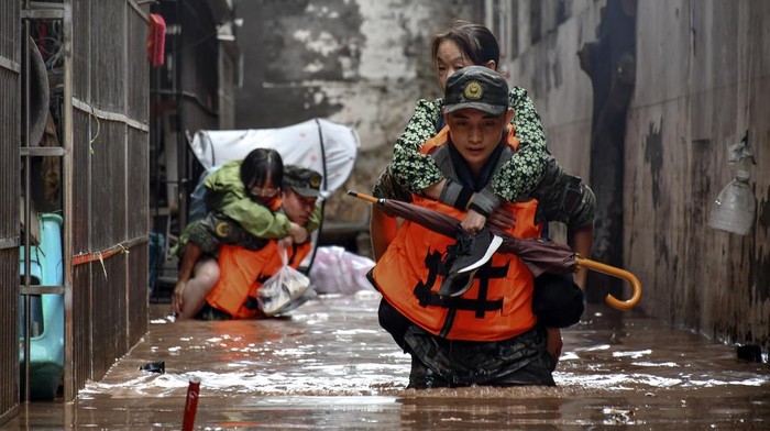 In this photo released by Xinhua News Agency, members of the Chinese People's Armed Police Force evacuate flood trapped residents in Wanzhou District, in southwest China's Chongqing Municipality, Tuesday, July 4, 2023. Heavy flooding has displaced thousands of people around China as the capital had a relative respite from sweltering heat. (Li Yuyang/Xinhua via AP)