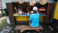 Seorang warga duduk santai di sebuah warung makan meski sedang terjadi banjir.
