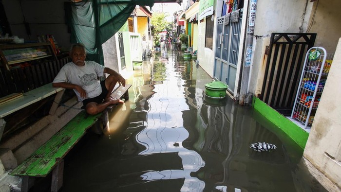 Penjual makanan melayani pembeli saat banjir rob menggenangi kampung Kalianak Timur, Surabaya, Jawa Timur, Rabu (5/7/2023). Pasang air laut yang tinggi akibat adanya fase bulan purnama menyebabkan perkampungan padat penduduk di kawasan tersebut tergenang banjir rob. ANTARA FOTO/Didik Suhartono/foc.
