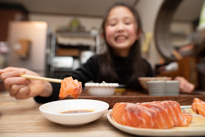 Girl eating sashimi with chopsticks