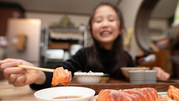 Girl eating sashimi with chopsticks