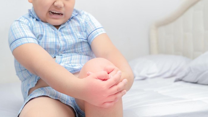 Ilustrasi Kanker Tulang pada Anak Obese fat boy suffering from knee pain and sit on bed, Healthy problem