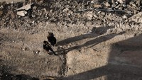 Warga Palestina berjalan di jalan yang rusak di kamp pengungsi.