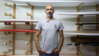 Paul Abbas berdiri di depan dereta papan selancar buatannya.  