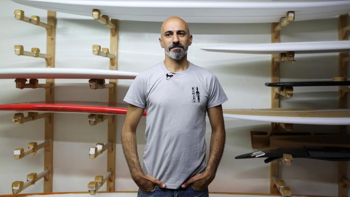Surfboard and paddle maker Paul Abbas stands in front of his surfboards in progress in his workshop in Halat, north of Beirut, Lebanon June 26, 2023. REUTERS/Emilie Madi