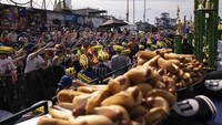 Orang-orang ramai berkumpul untuk menyaksikan lomba makan hot dog yang meriah tersebut.  