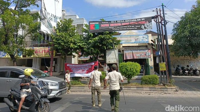 Satpol PP Kota Solo mencopoti spanduk penolakan aksi people power di jalanan, Rabu (5/7/2023).