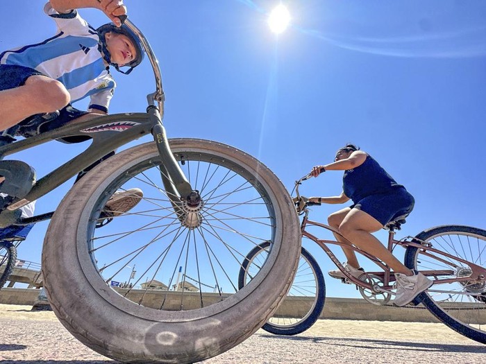 People cruise along the path north of the pier in Huntington Beach, Calif., Friday, June 30, 2023. (Jeff Gritchen/The Orange County Register via AP)