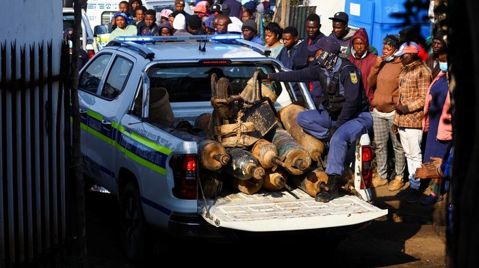Ini Tambang Ilegal yang Tewaskan 24 Warga di Afsel Onlookers gather near the scene of a suspected gas leak thought to be linked to illegal mining, in the Angelo shack settlement, near Boksburg, east of Johannesburg, South Africa July 6, 2023. REUTERS/Siphiwe Sibeko
