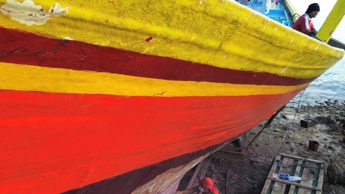 Pekerja menyelesaikan pembersihan bodi kapal nelayan berbahan viber di Teluk Kendari, Sulawesi Tenggara, Kamis (6/7/2023). Jasa pembersihan dan perbaikan serta pengecatan kapal nelayan tersebut berkisar dari Rp 70 juta hingga Rp 100 juta per unitnya untuk kapal 30 gross tonnage. ANTARA FOTO/Jojon.