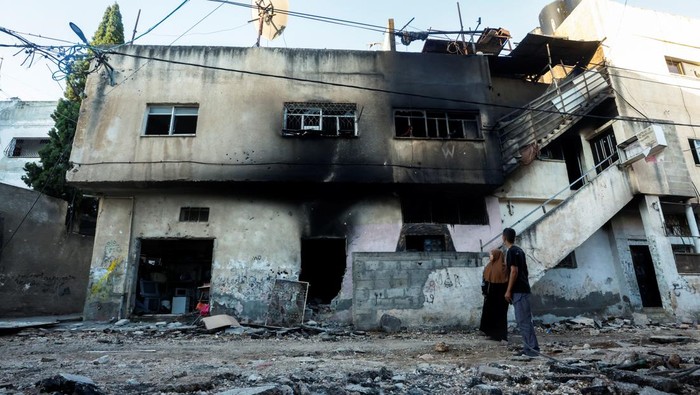 Palestinians look at a damaged building, after the Israeli armys withdrawal from the Jenin camp, in Jenin, in the Israeli-occupied West Bank July 5, 2023. REUTERS/Mohamad Torokman