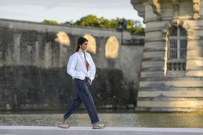 Desainer Valentino, Pierpaolo Piccioli, dibuka dengan penampilan model Kaia Gerber sebagai first face. Kaia yang terakhir kali eksis di catwalk akhir tahun lalu membuat comeback-nya terasa memukau dalam balutan blus putih dengan gaya braless setelah kancing bagian atas dibiarkan terbuka. (Foto: AP Photo/Christophe Ena)
