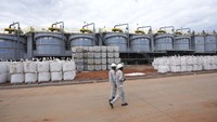 Para pekerja berjalan melewati kantong-kantong berisi lithium di lahan pabrik pemrosesan Prospect Lithium Zimbabwe. Permintaan terhadap jenis logam ini semakin meningkat karena tingginya kebutuhan baterai untuk kendaraan listrik.