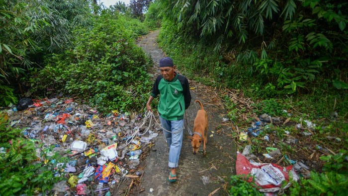 Persoalan sampah di desa wisata Pariangan Warga bersama anjingnya melintas di antara sampah plastik yang berserakan di pinggir hutan, Nagari Pariangan, Tanah Datar, Sumatera Barat, Kamis (6/7/2023). Warga desa wisata yang dijuluki sebagai Desa Terindah di Dunia itu terpaksa membuang sampah ke sungai dan ke pinggir hutan karena tidak memiliki lokasi pembuangan sampah sementara yang memadai. ANTARA FOTO/Iggoy el Fitra/tom.