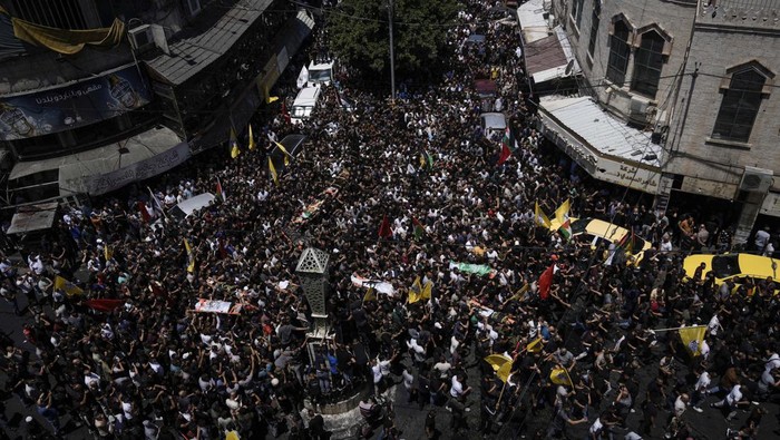 Mourners carry the body of a Palestinian man draped in the flag of the Islamic Jihad militant group during their funeral, in the Jenin refugee camp, West Bank, Wednesday, July 5, 2023. The Israeli military says it withdrew its troops from the camp on Wednesday, ending an intense two-day operation that killed at least 13 Palestinians, drove thousands of people from their homes and left a wide swath of damage in its wake. One Israeli soldier was also killed. (AP Photo/Majdi Mohammed)