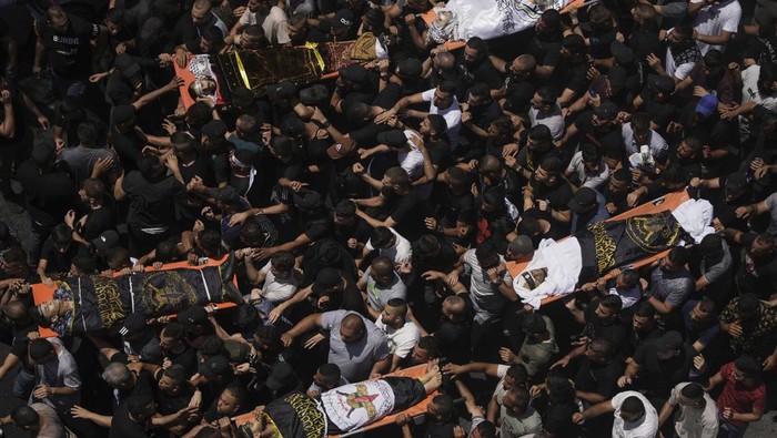 Ribuan Orang Anter Pemakaman Korban Tewas Serangan Israel Mourners carry the body of a Palestinian man draped in the flag of the Islamic Jihad militant group during their funeral, in the Jenin refugee camp, West Bank, Wednesday, July 5, 2023. The Israeli military says it withdrew its troops from the camp on Wednesday, ending an intense two-day operation that killed at least 13 Palestinians, drove thousands of people from their homes and left a wide swath of damage in its wake. One Israeli soldier was also killed. (AP Photo/Majdi Mohammed)