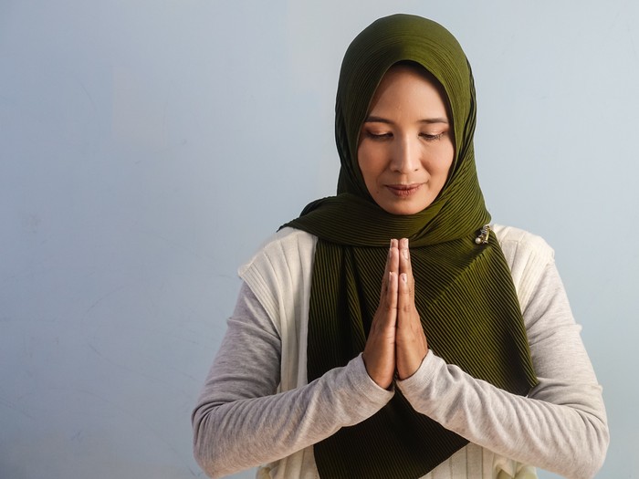 A portrait of Asian woman posing for thank you body language by putting her both hand together in the front. Copy space, empty space.